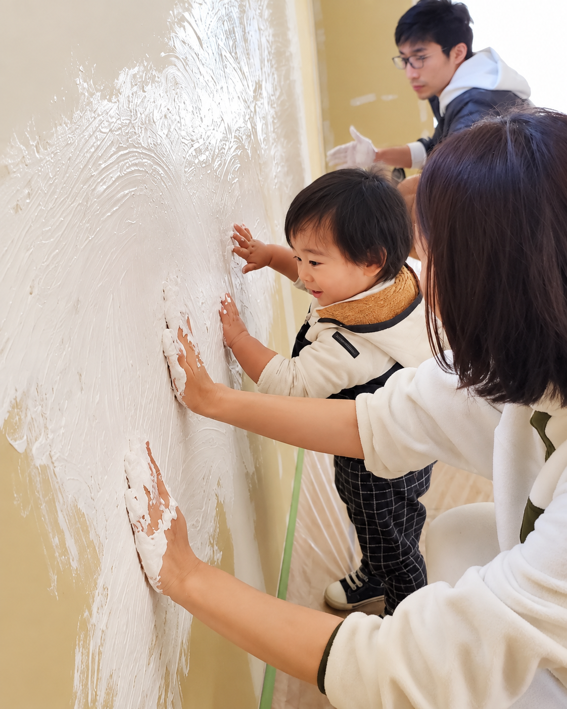 お子さんとお母さんが一緒に壁を塗る様子